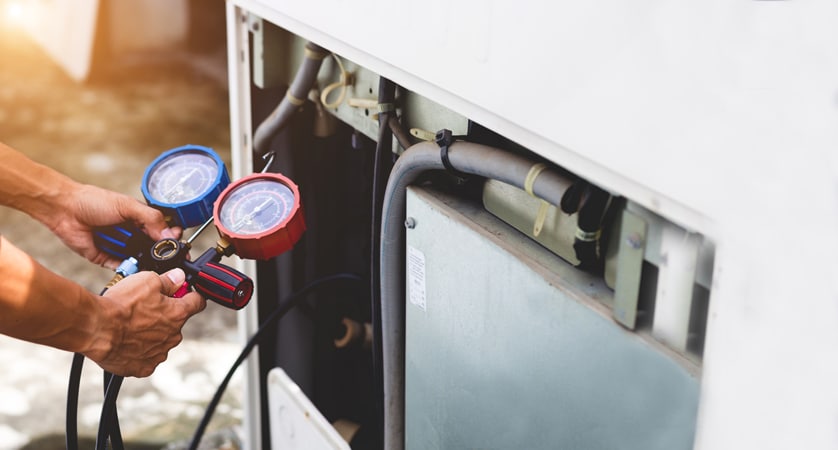 AC Repair technician using measuring equipment to repair an Air Conditioner
