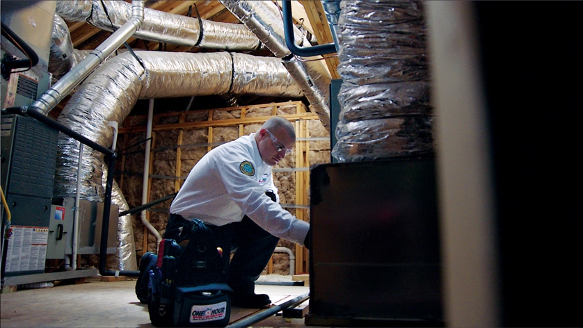 OH Technician in an attic with the air duct & venitilation system