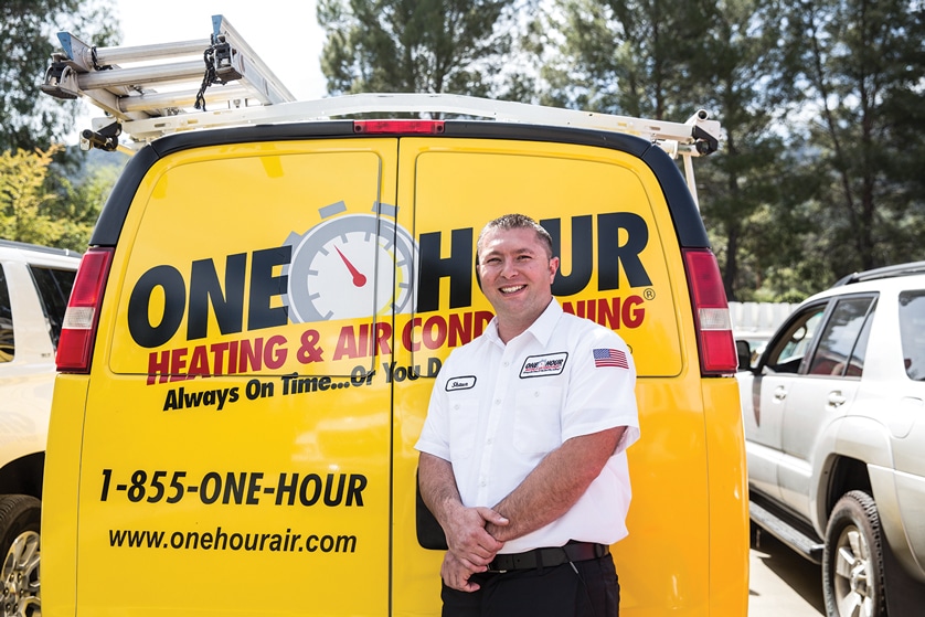One Hour Heating & Air Conditioning technician standing in front of a company van.
