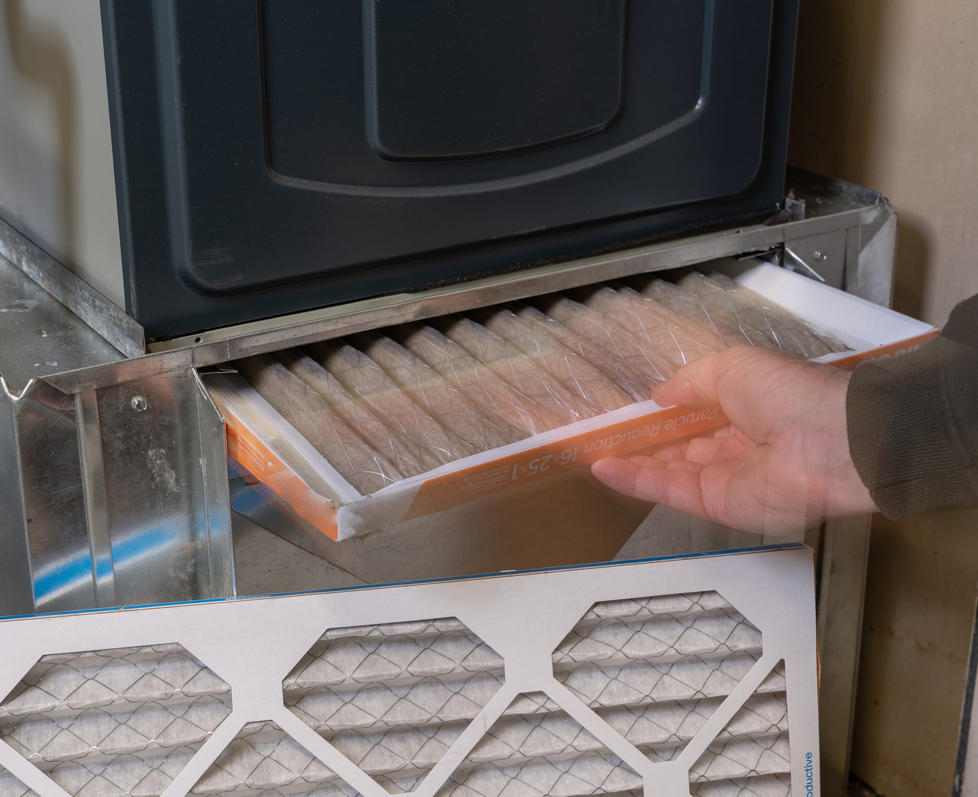 Replacing dirty furnace filter in home by man, Seasonal HVAC Preparation.
